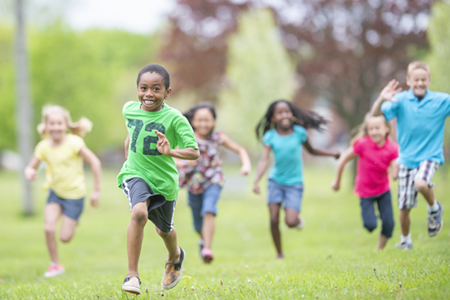 A group of young people running through the grass in a park