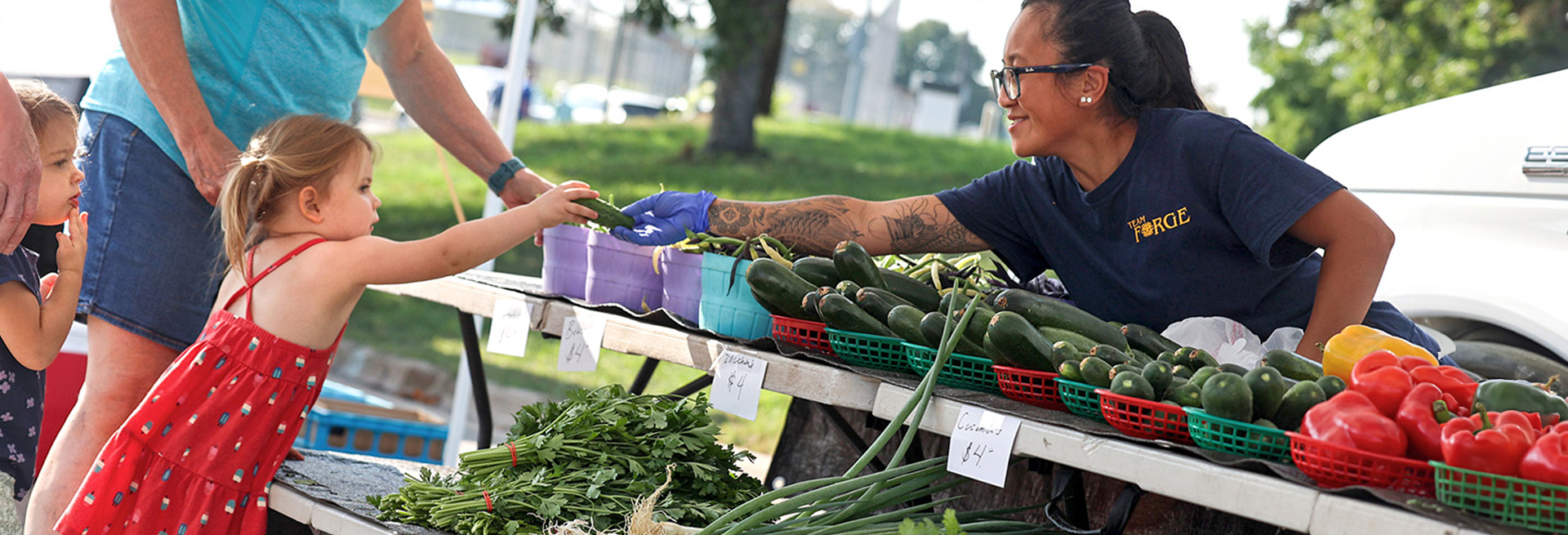 Plymouth Farmers Market vendor hands a child a cucumber